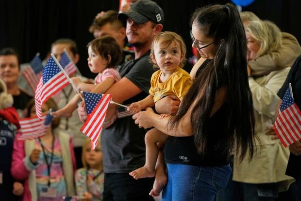 Refugiados africâneres da África do Sul seguram bandeiras americanas ao chegarem ao aeroporto Dulles em Washington, em maio passado. Fotografia: Julia Demaree Nikhinson/AP